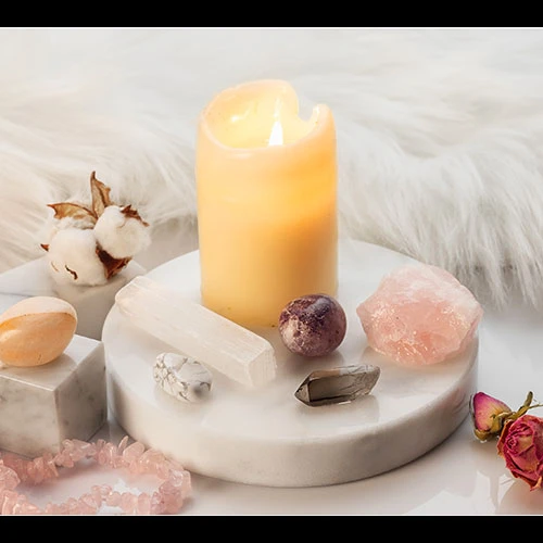 A candle burning with some crystals around the base.